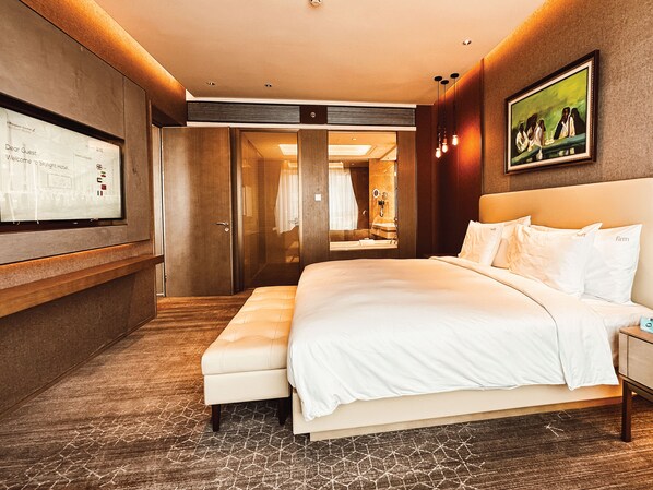 A hotel room with a large bed, a seating area, a television, and a mirror.