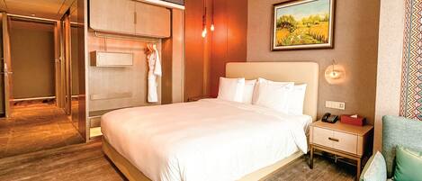A hotel room with a large bed, a bedside table with a lamp, a painting on the wall, and a wardrobe.
