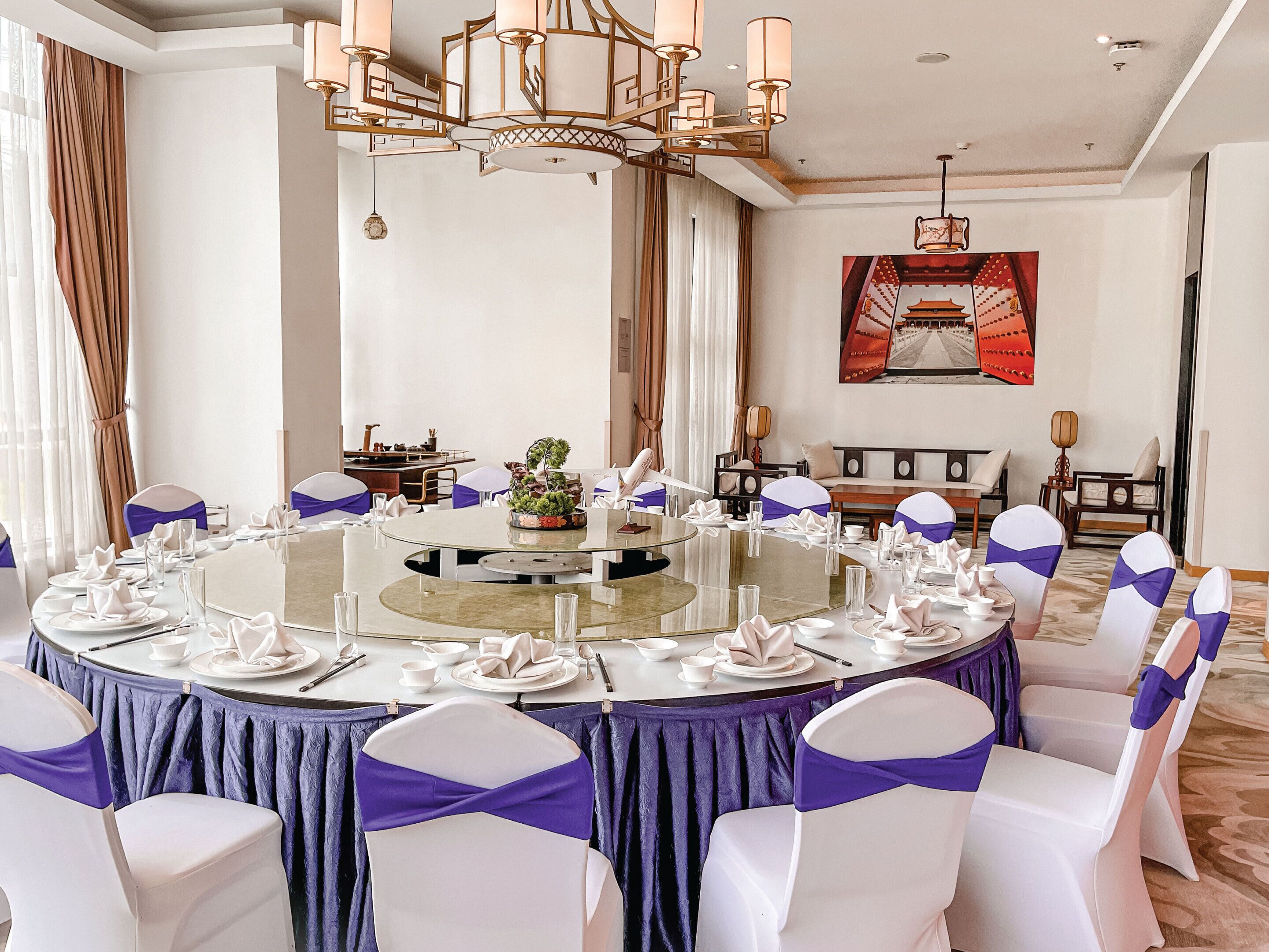 A round table with white chairs, purple sashes, and a central floral arrangement.