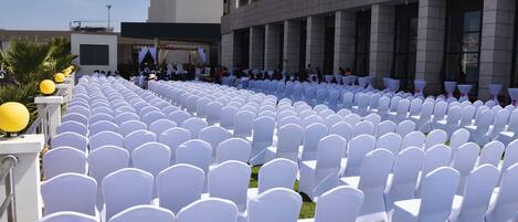 Rows of white chairs arranged outdoors, likely for an event, with a building in the background.