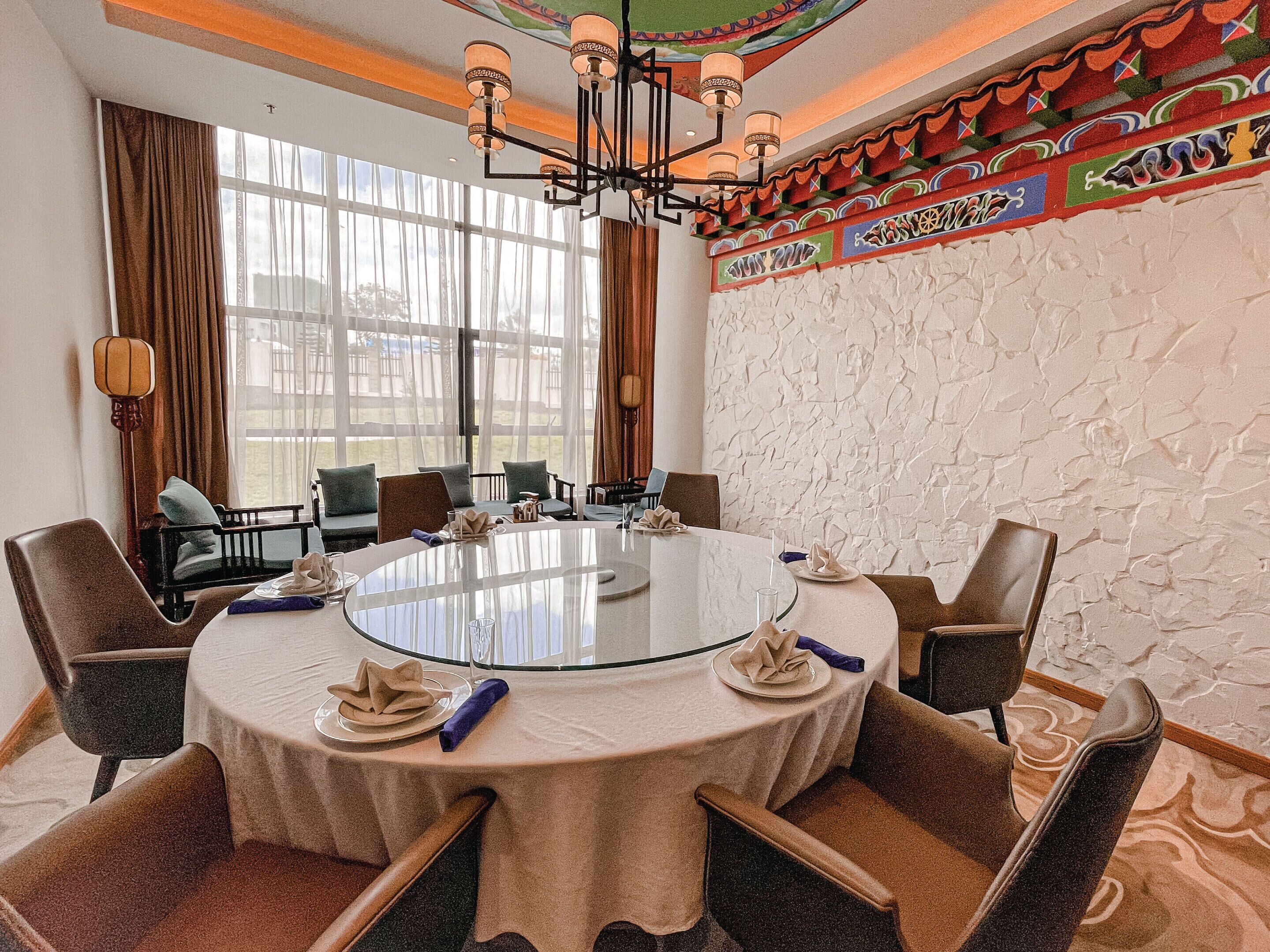 A conference room with a round glass table, brown leather chairs, and a decorative ceiling.