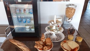 Un bufé de desayuno con pasteles, sándwiches y zumo.