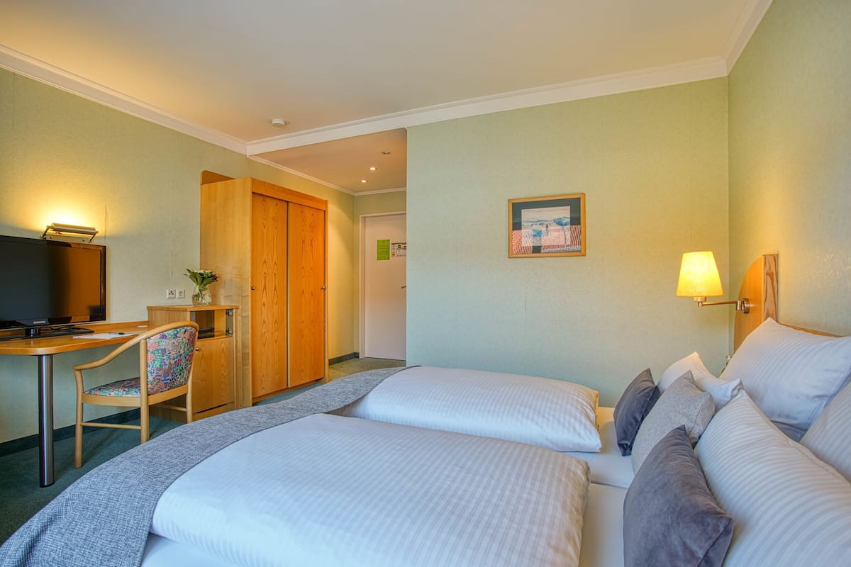 A hotel room with a bed, a desk, a chair, and a television.