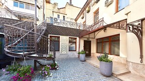A courtyard with a spiral staircase, potted plants, and a bench. - Shato Luxe Hotel (Odesa)