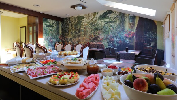 A buffet with various food items and a tropical mural in the background. - Shato Luxe Hotel (Odesa)