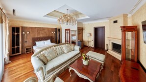 A spacious bedroom with a large bed, a sofa, a coffee table, and a fireplace. - Shato Luxe Hotel (Odesa)