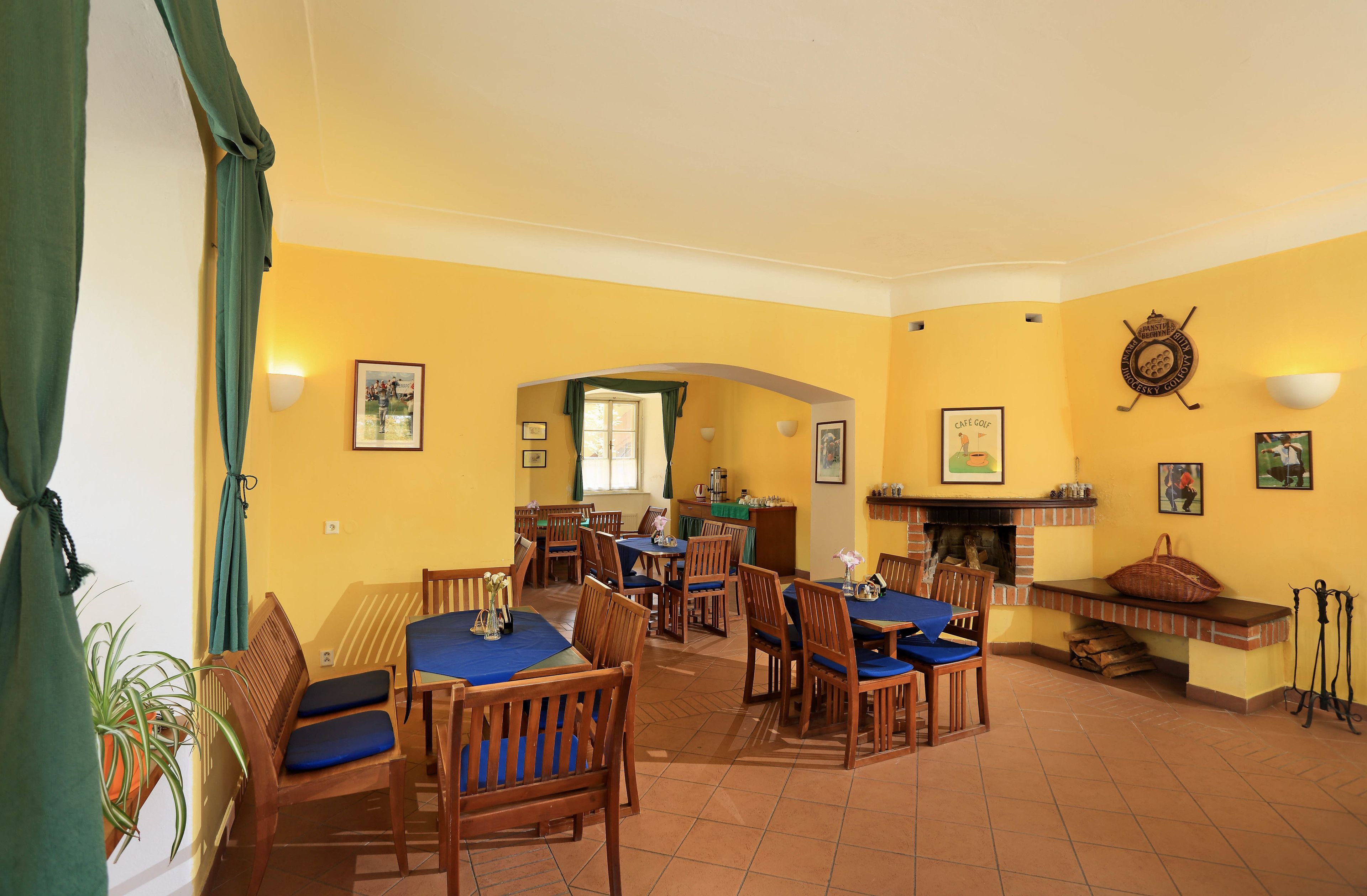 A dining area with wooden tables and chairs, a brick fireplace, and yellow walls.