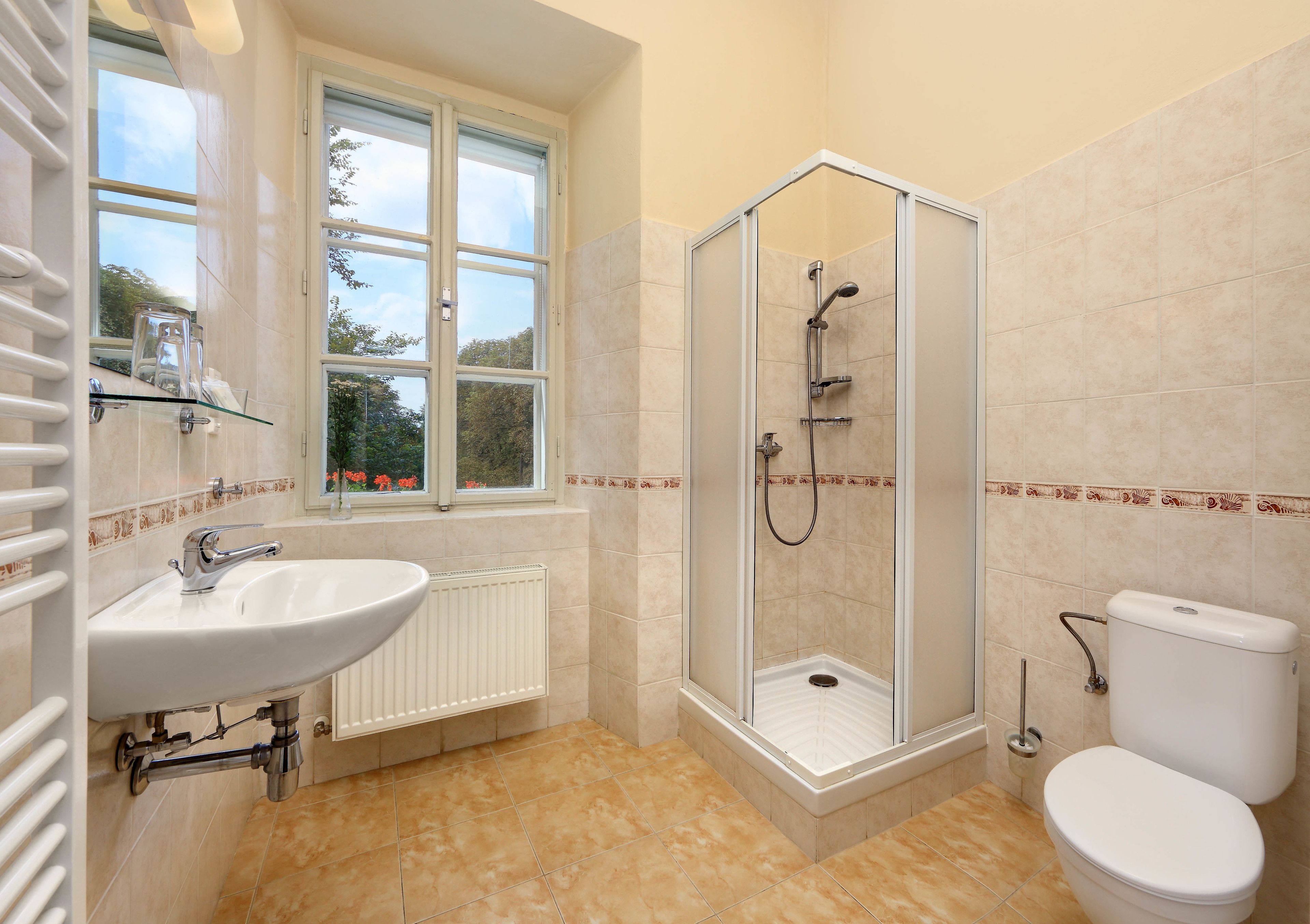 Un baño con ducha de vidrio, lavamanos blanco y retrete.