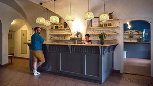 A bar area with a counter, hanging wicker lamps, shelves with glasses and bottles, and a blue accent wall. - Penzion Černická obora (Sudomerice u Bechyne)