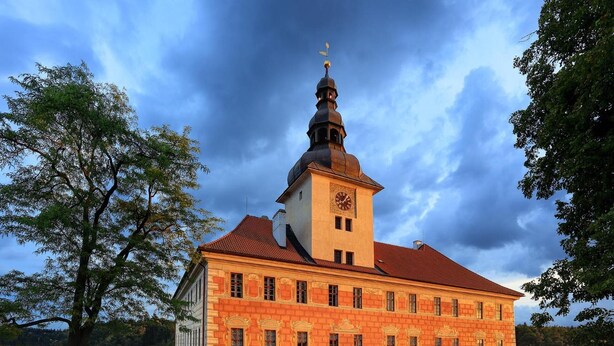 A large, historic building with a prominent clock tower and a symmetrical facade. - Penzion Černická obora (Sudomerice u Bechyne)