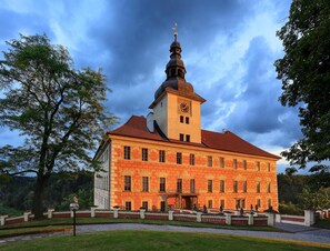 A large, historic building with a prominent clock tower and a symmetrical facade. - Penzion Černická obora (Sudomerice u Bechyne)