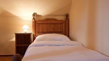 A single bed with a wooden headboard in a room with a sloped ceiling.
