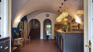 A spacious hallway with a central staircase, a bar area with a view, and a dining setup with wicker chairs. - Penzion Černická obora (Sudomerice u Bechyne)