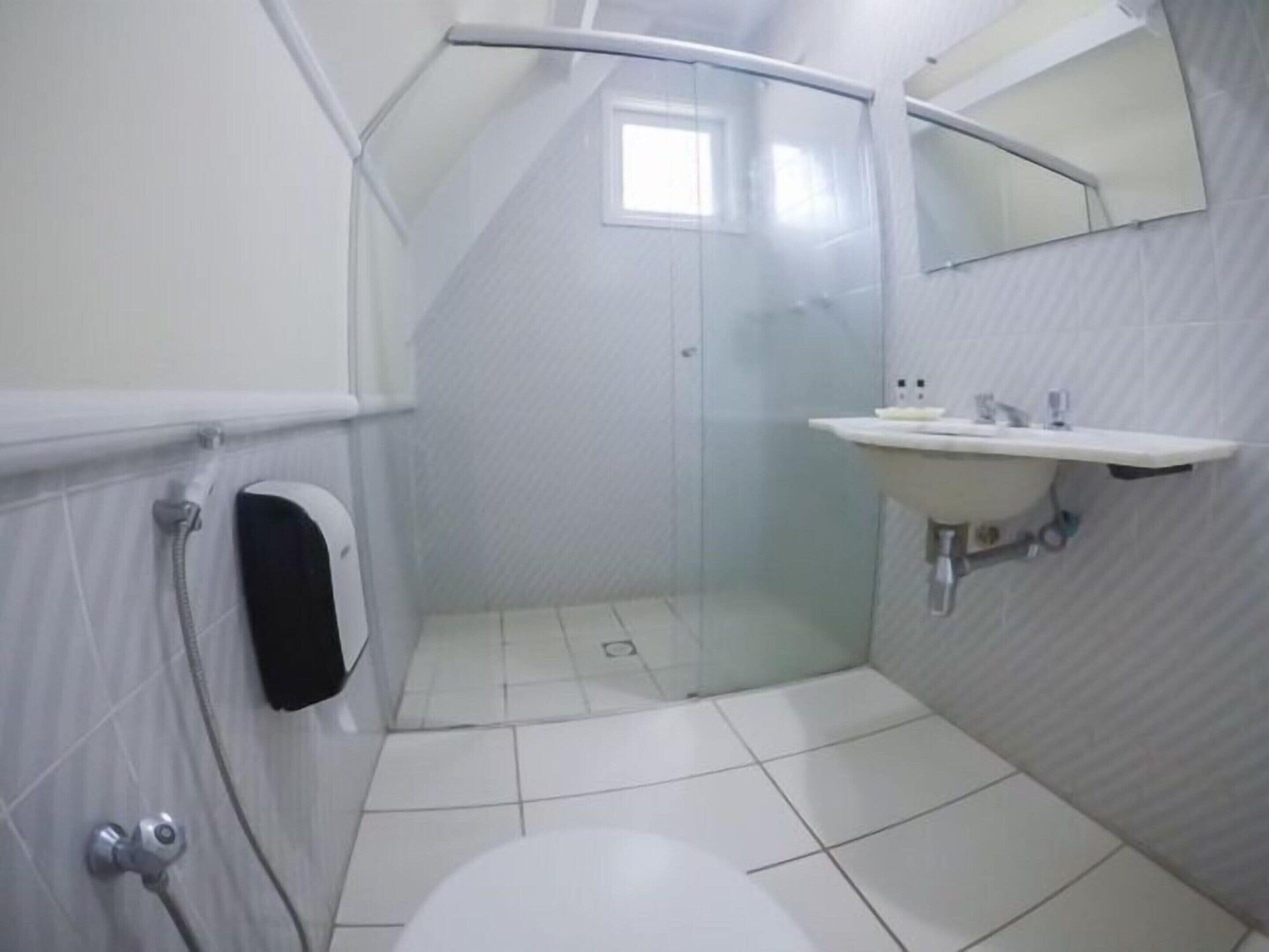 Une salle de bain moderne avec une douche à parois de verre, un lavabo blanc et un miroir au-dessus.