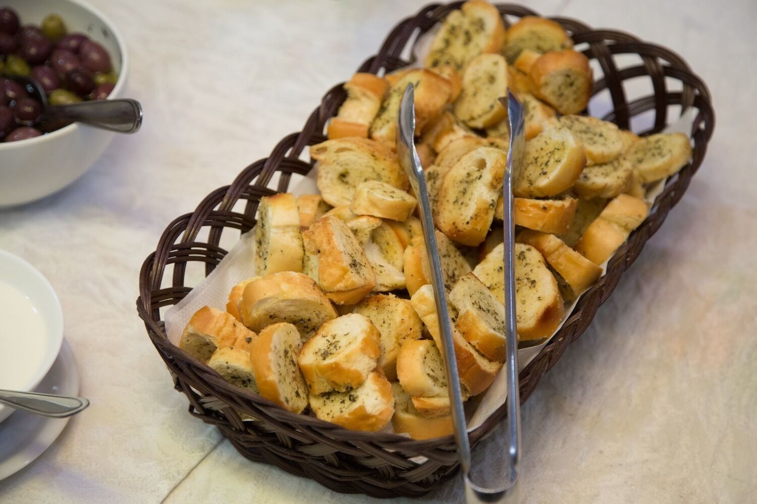 Een mand gevuld met sneetjes knoflookbrood op een tafel.