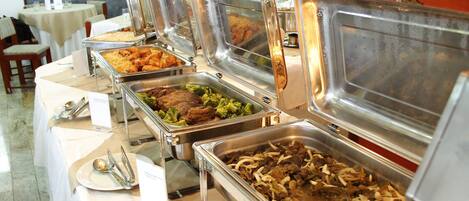 Un bufé con varias estaciones de comida, que incluye opciones como carne, verduras y arroz.