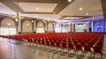 Un'ampia sala con file di sedie rosse e un palco sul davanti.