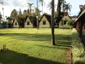 A row of yellow buildings with dark roofs, surrounded by well-maintained grass and palm trees. - Hotel Dona Beja (Araxá)