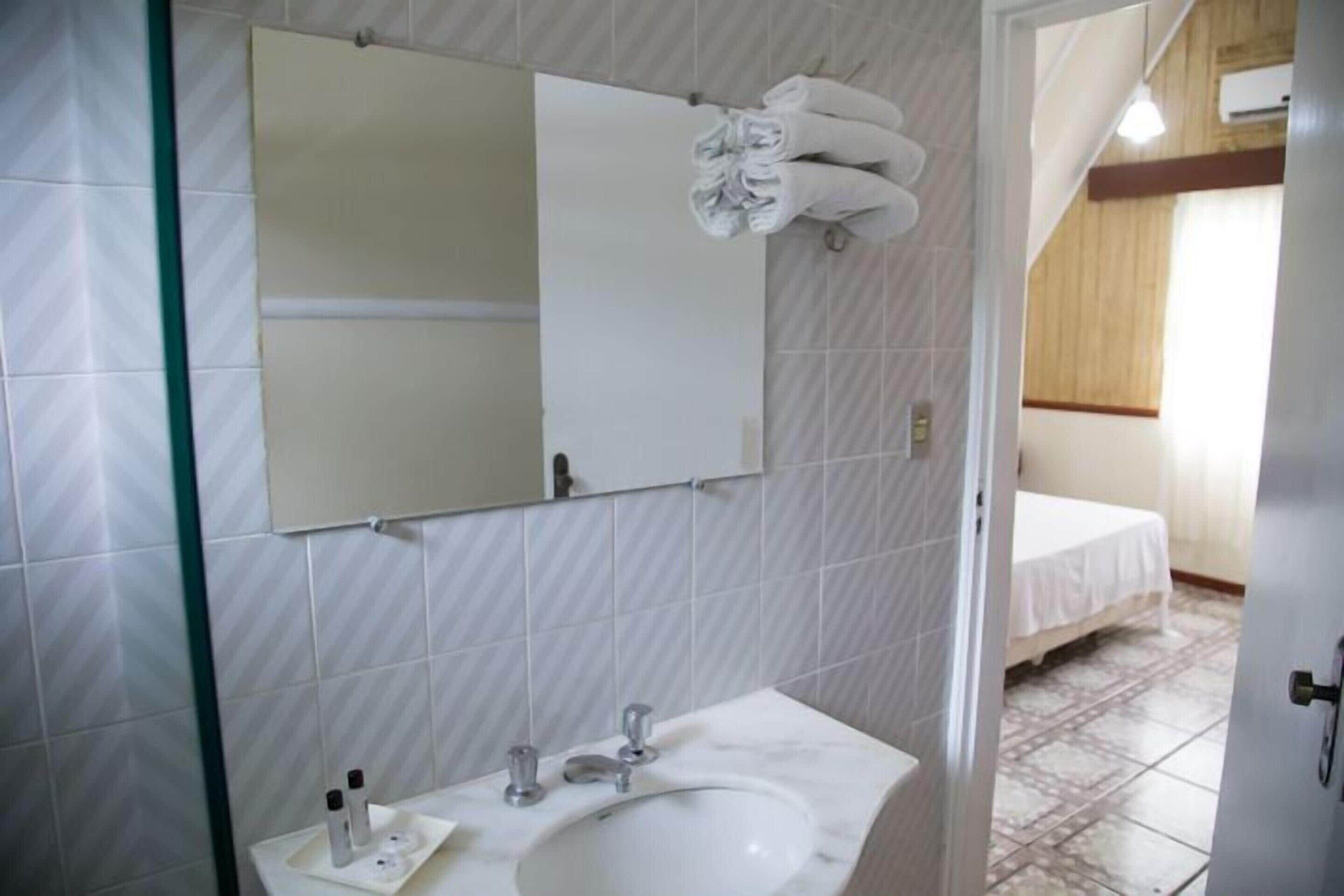 A bathroom with a white sink, mirror, and towel rack.
