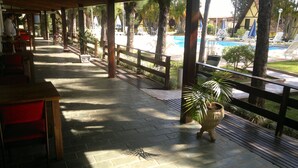 A covered outdoor area with a pool, wooden benches, and potted plants. - Hotel Dona Beja (Araxá)