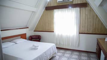 Una habitación de hotel con una cama, una silla, un escritorio y un equipo de aire acondicionado.