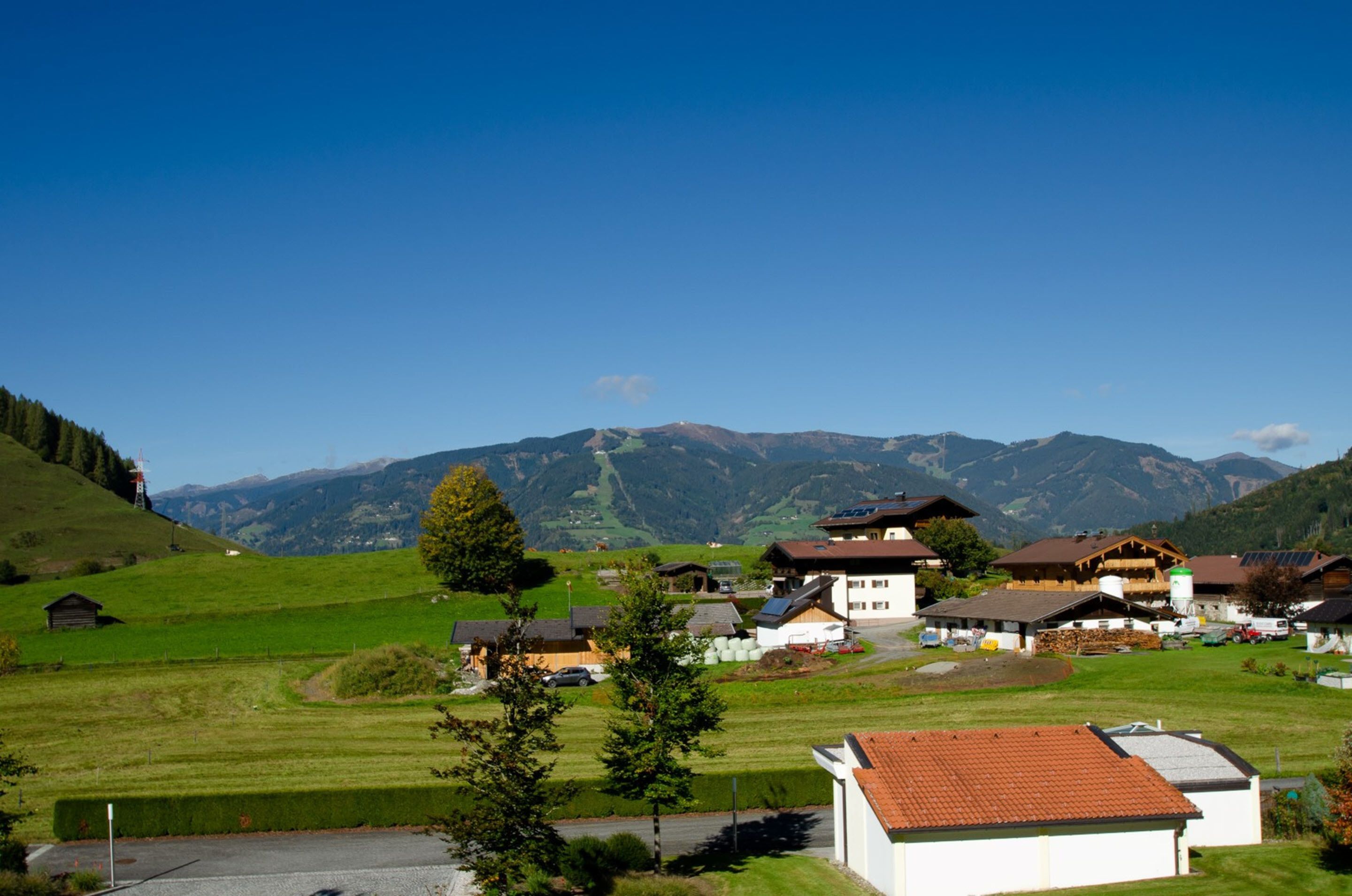 A rural village with traditional houses, a clear sky, and mountains in the background.