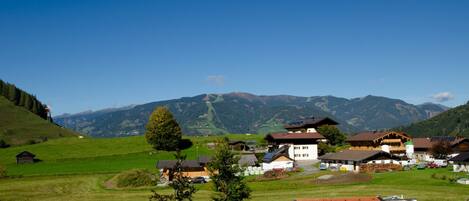 A rural village with traditional houses, a clear sky, and mountains in the background.
