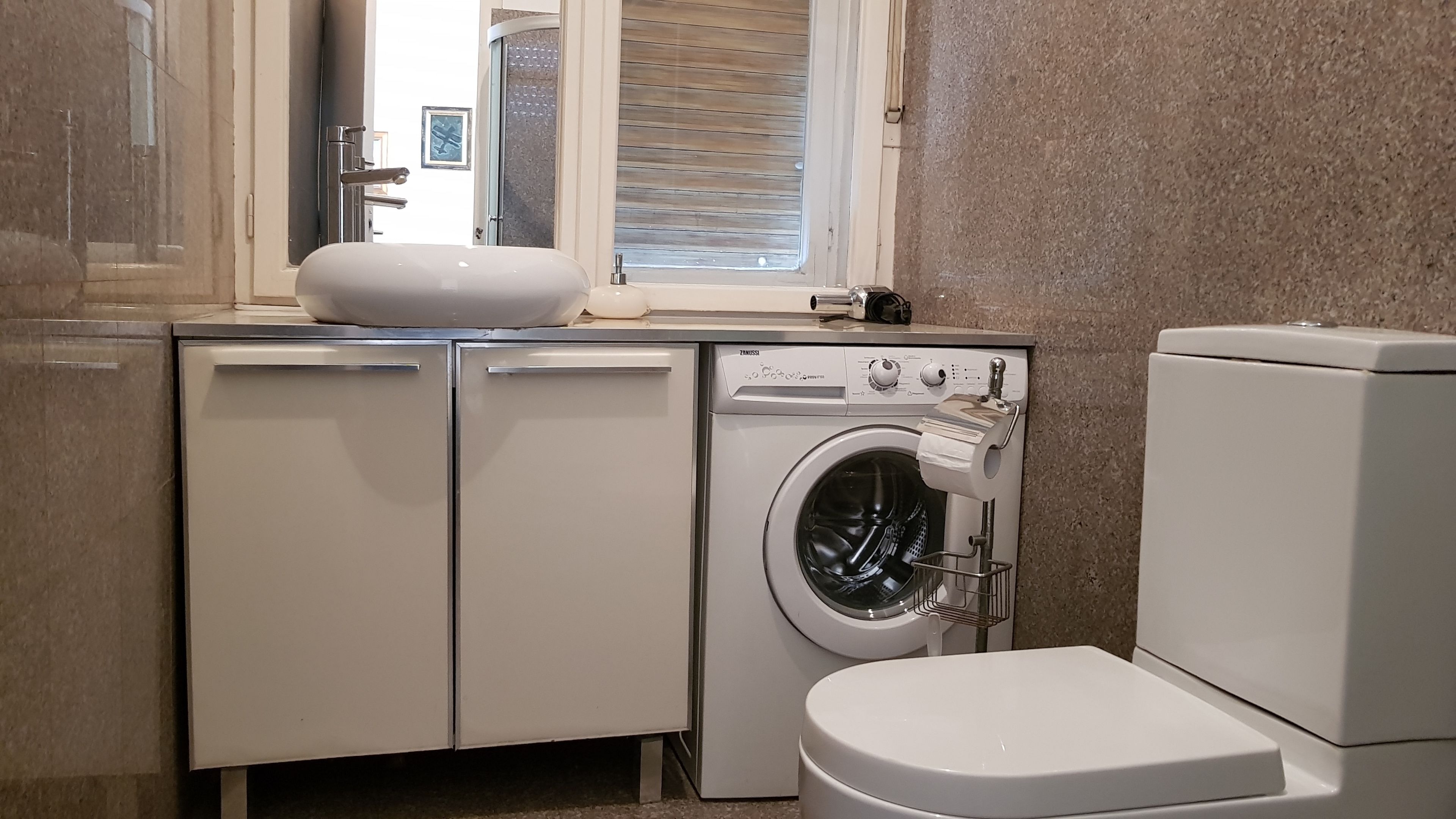 Uma casa de banho compacta com máquina de lavar, sanita e lavatório.