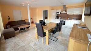 A compact living space with a dining area, kitchenette, and a sofa. - Penthouses Zell am See (Zell am See)