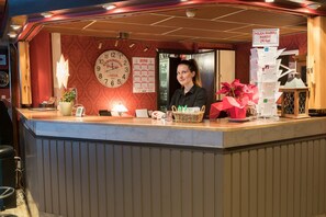 Un comptoir de réception d’hôtel avec une horloge, un calendrier et un panneau indiquant le prix du minibar.