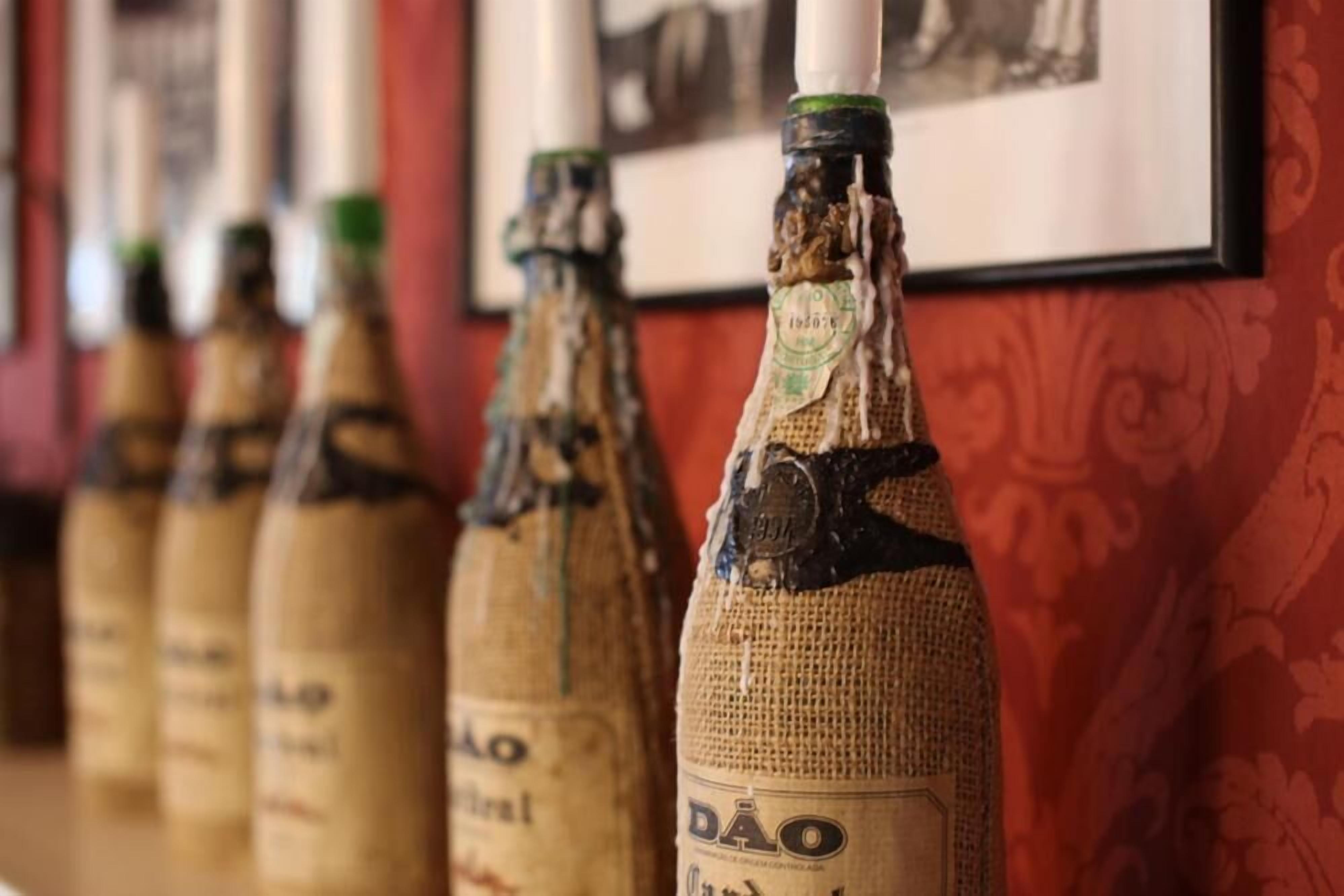 A row of bottles with labels, some with visible damage, against a patterned wall.