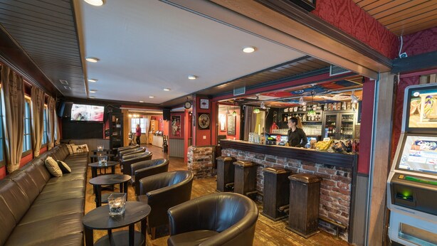 A bar area with leather seating, a counter, and a jukebox. - Hotel Kievari Ylitornio (Ylitornio)