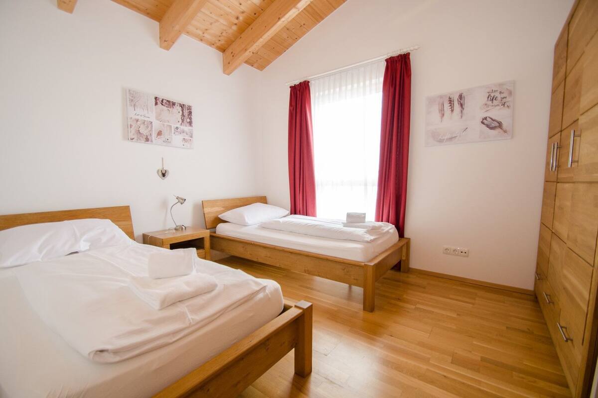 Une chambre avec deux lits, un plancher en bois, un plafond en bois et une armoire.