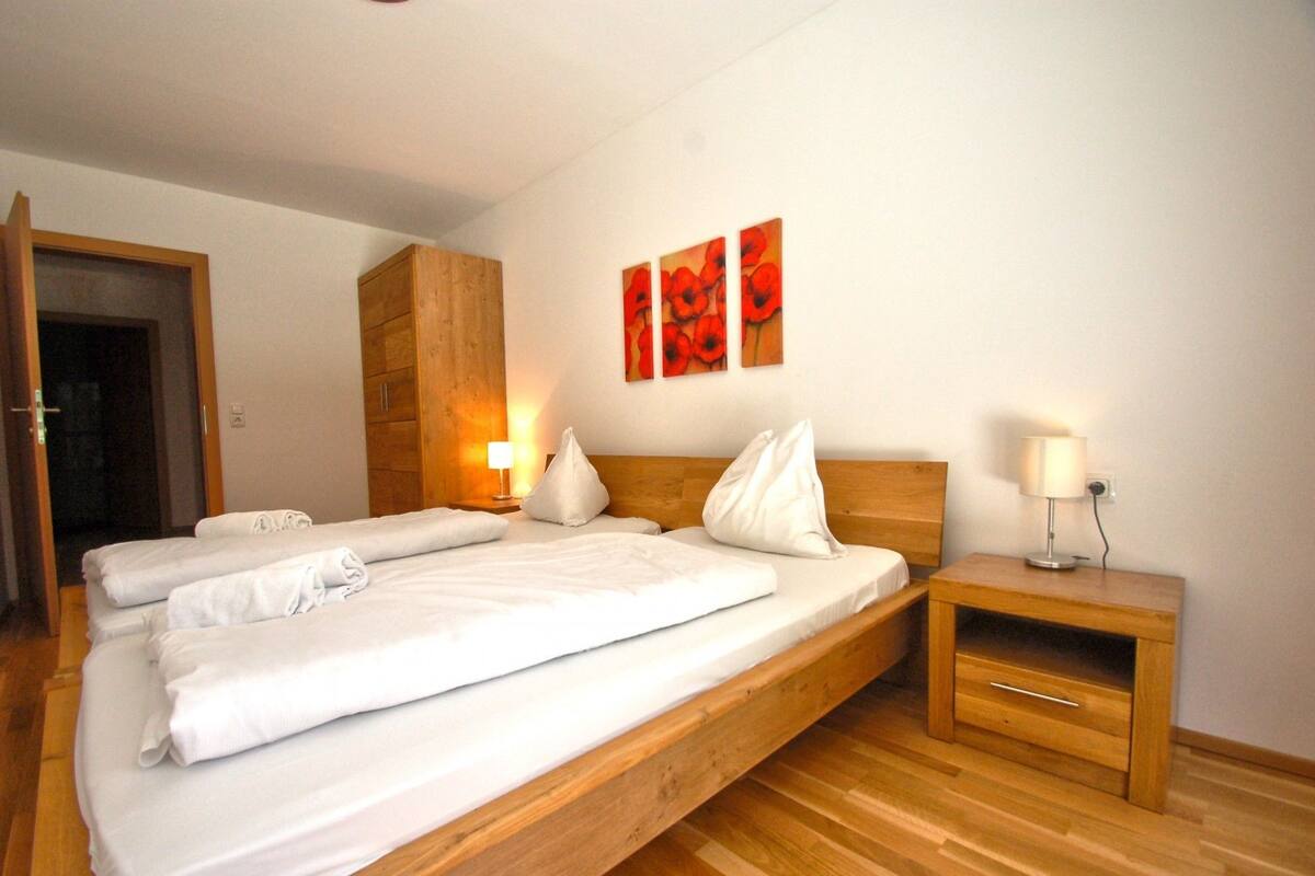 Une chambre d’hôtel avec un grand lit, une tête de lit en bois, deux tables de chevet avec des lampes et une armoire en bois.