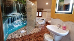 A bathroom with a waterfall mural, a bathtub, a sink, and a mirror. - Pension Bomätscher (Koenigstein)