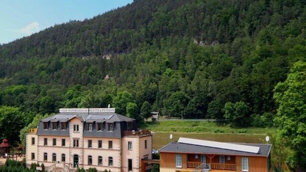 A building with a sloped roof, multiple windows, and a sign indicating it is a state hotel. - Pension Bomätscher (Koenigstein)