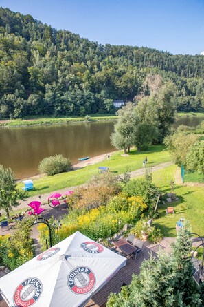 A lakeside view with a tent, outdoor seating, and a boat dock. - Campingplatz am Treidlerweg (Koenigstein)