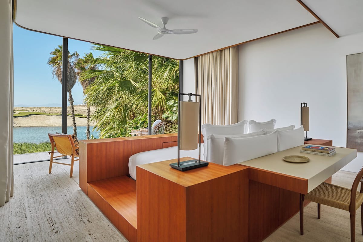A modern room with a wooden desk, a white sofa, and a view of a beach and palm trees.