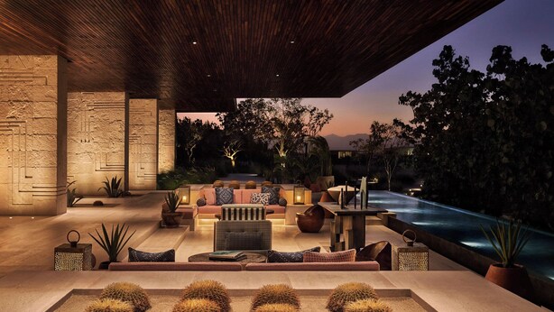 A modern outdoor lounge area with a stone wall, seating, and a pool.