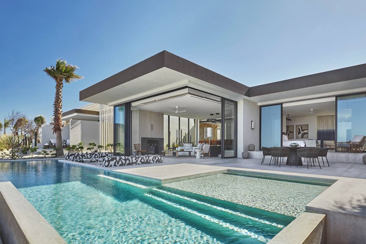 A modern house with a swimming pool, outdoor seating, and a large patio area.