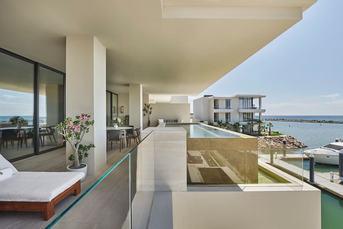 A modern balcony with a glass railing overlooking a pool and marina.