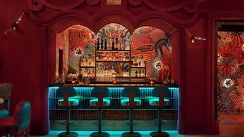 Zona de bar con decoración en rojo y azul, que incluye una barra y tres taburetes.