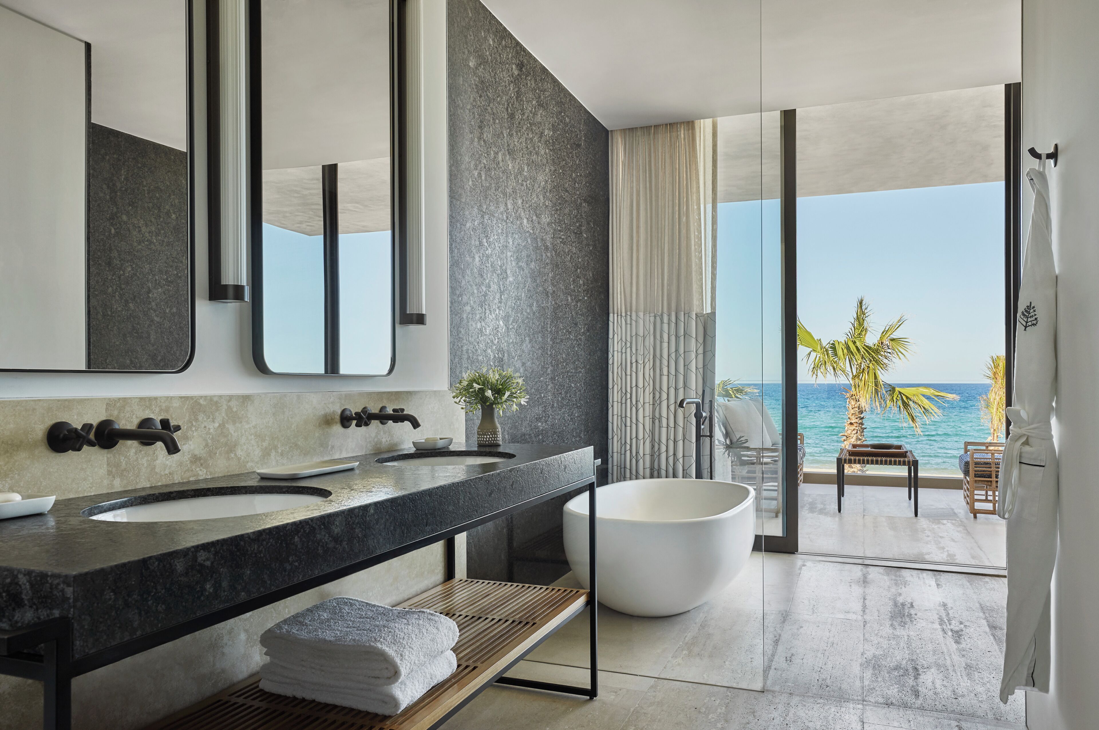 Ein modernes Badezimmer mit einem großen Waschbecken, einer Badewanne und Blick auf den Ozean.