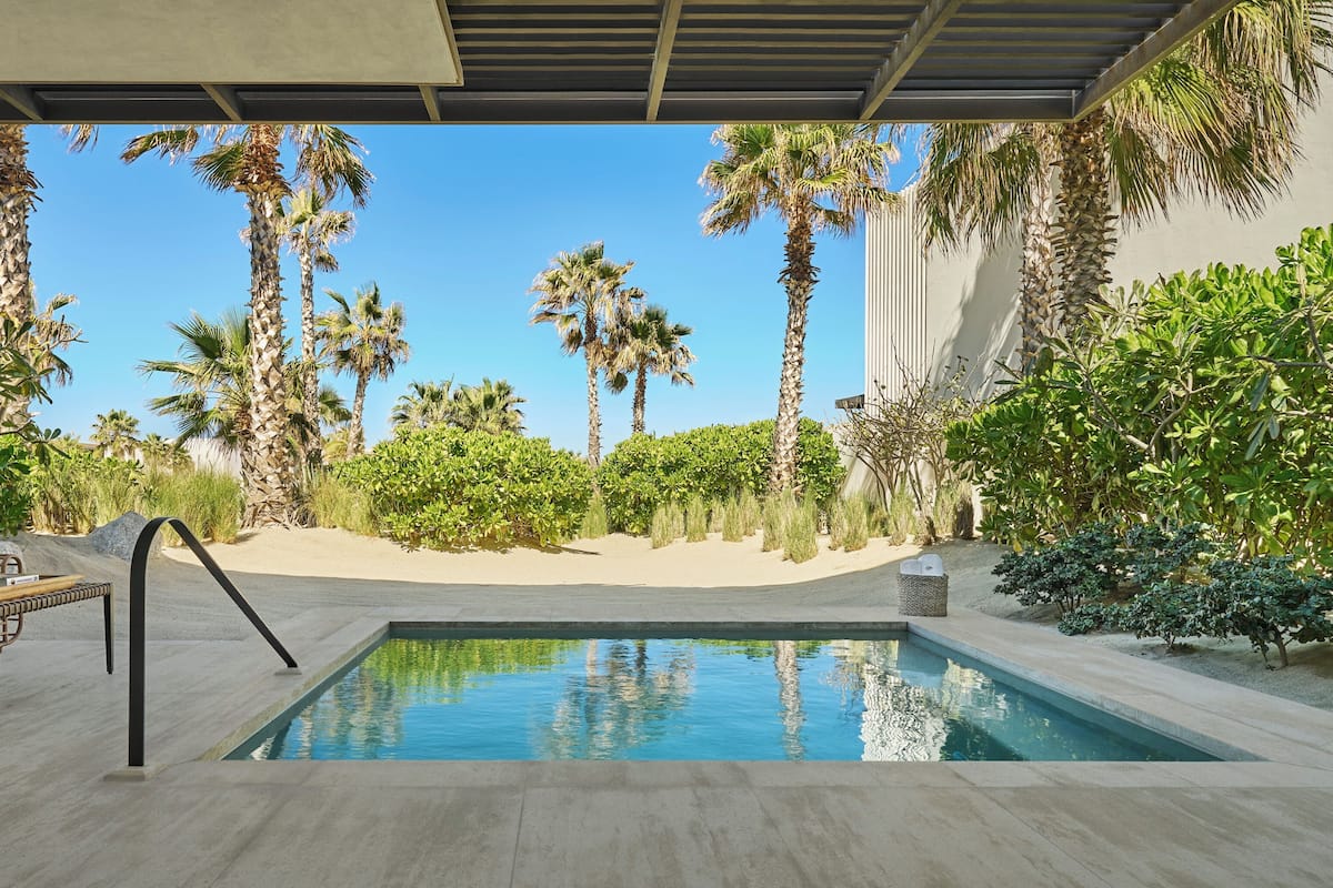 A pool area with a clear view of palm trees and a sandy beach.
