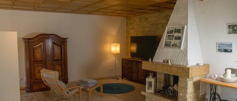 Una sala de estar con chimenea de piedra, muebles de madera y televisor.