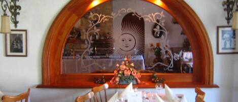 A dining area with a table set for four, chairs, and a decorative mirror above the table.