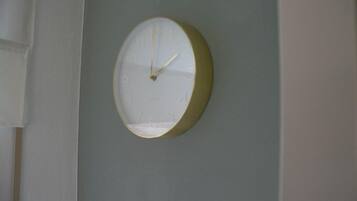 A round wall clock with a white face and gold trim, mounted on a light blue wall.