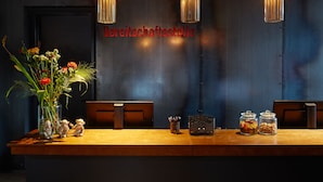 A reception desk with a vase of flowers, two glass jars with candies, and a sign reading "Bereitschaftsstelle". - hotel friends Zeche Zollverein - Essen (Essen)
