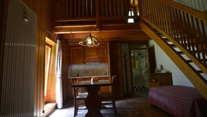 Un intérieur en bois comprenant une table à manger, des chaises, un escalier et un lit.