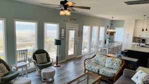 A spacious living area with a large window, a ceiling fan, and a dining area with a view.